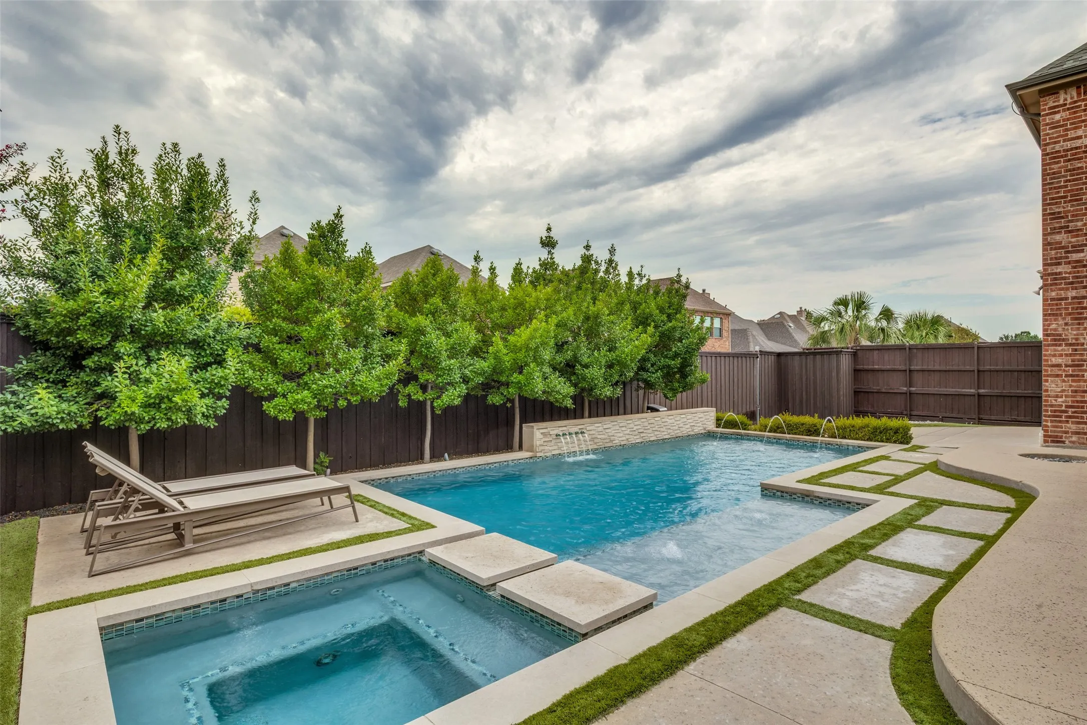 Rectangular swimming pool with integrated spa and waterfall feature