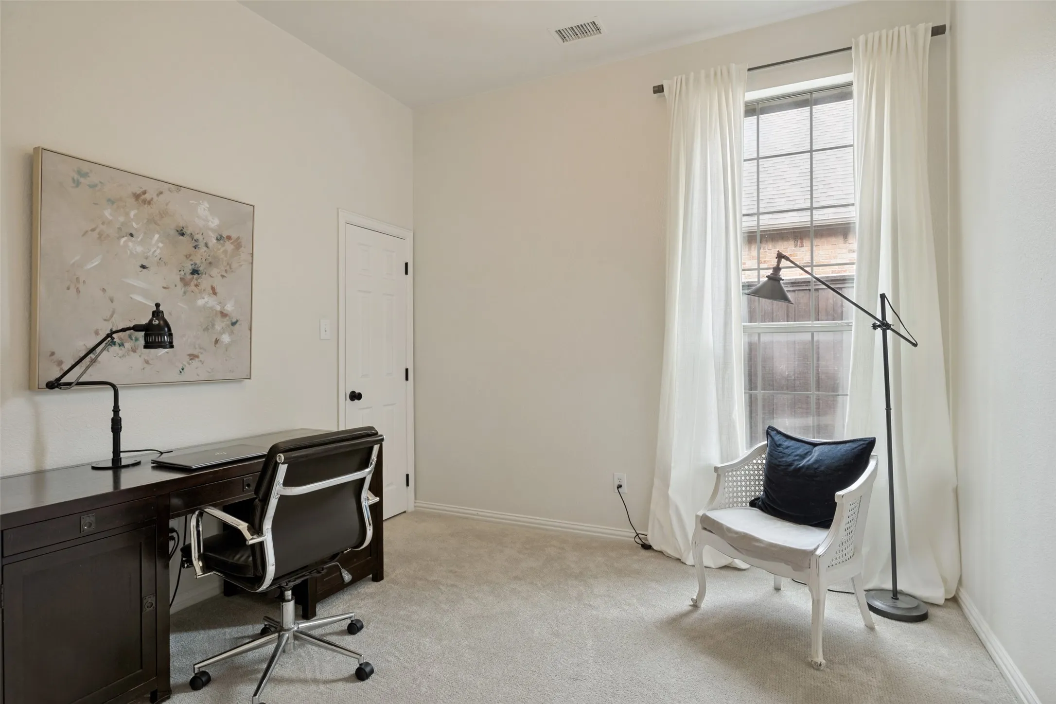 Carpeted room featuring a white interior door with black hardware, a large window with white curtains, and light-colored walls