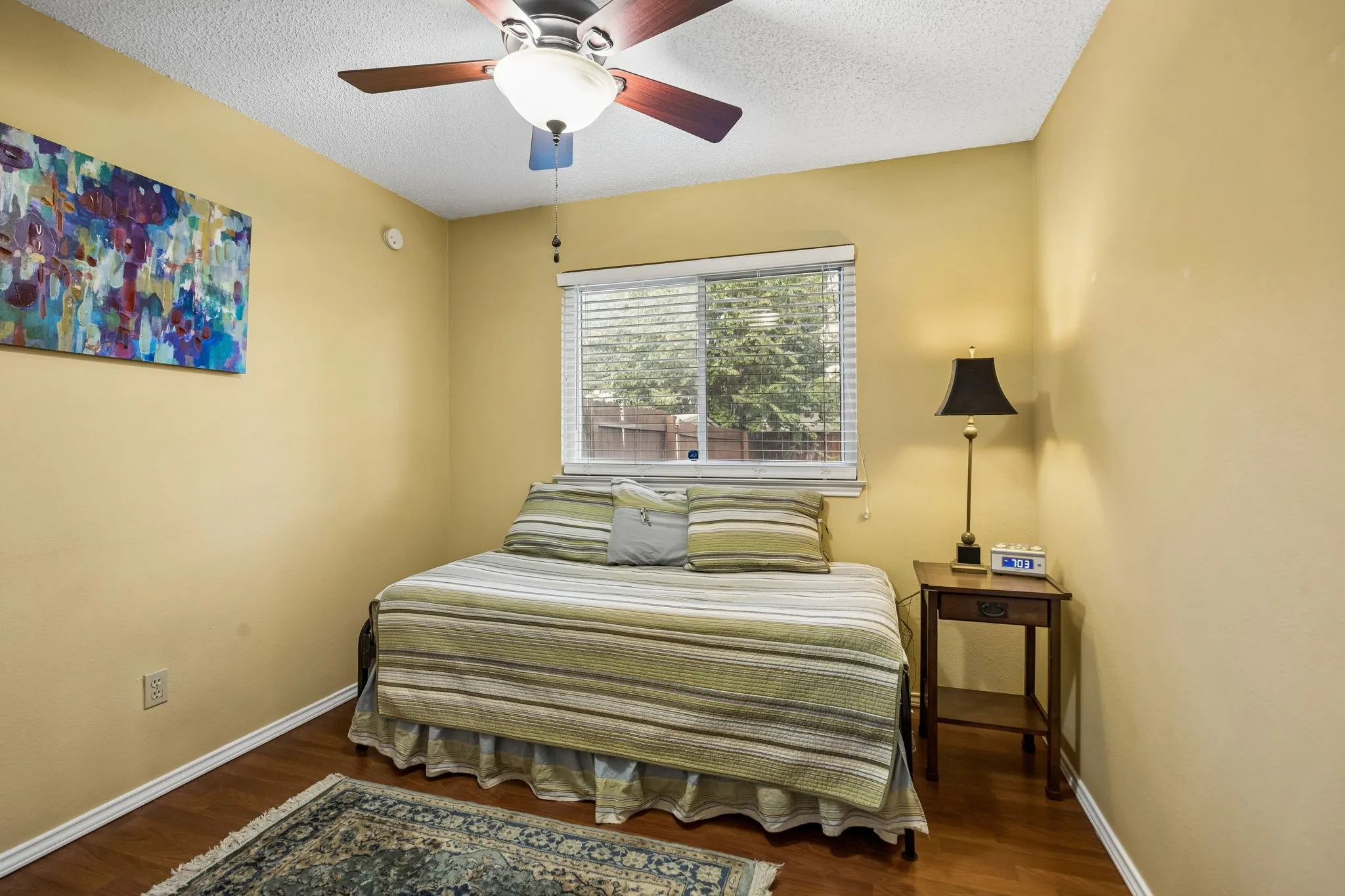 Wood-finish flooring, ceiling fan with light fixture, and window with blinds