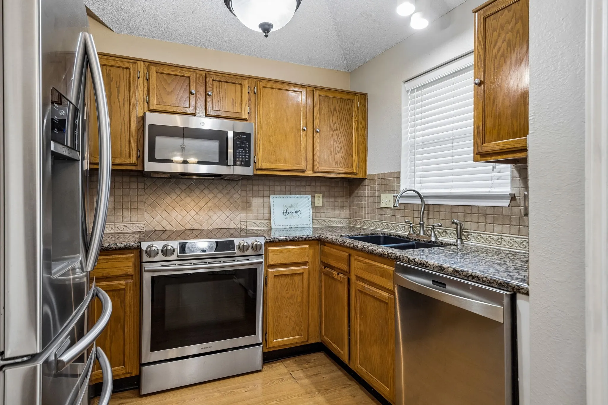 Kitchen featuring wood cabinetry, stainless steel appliances, speckled countertops, and a tiled backsplash