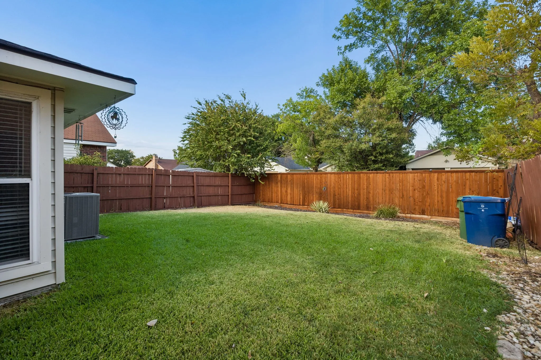 Expansive grassy yard area with wood fencing and mature perimeter trees