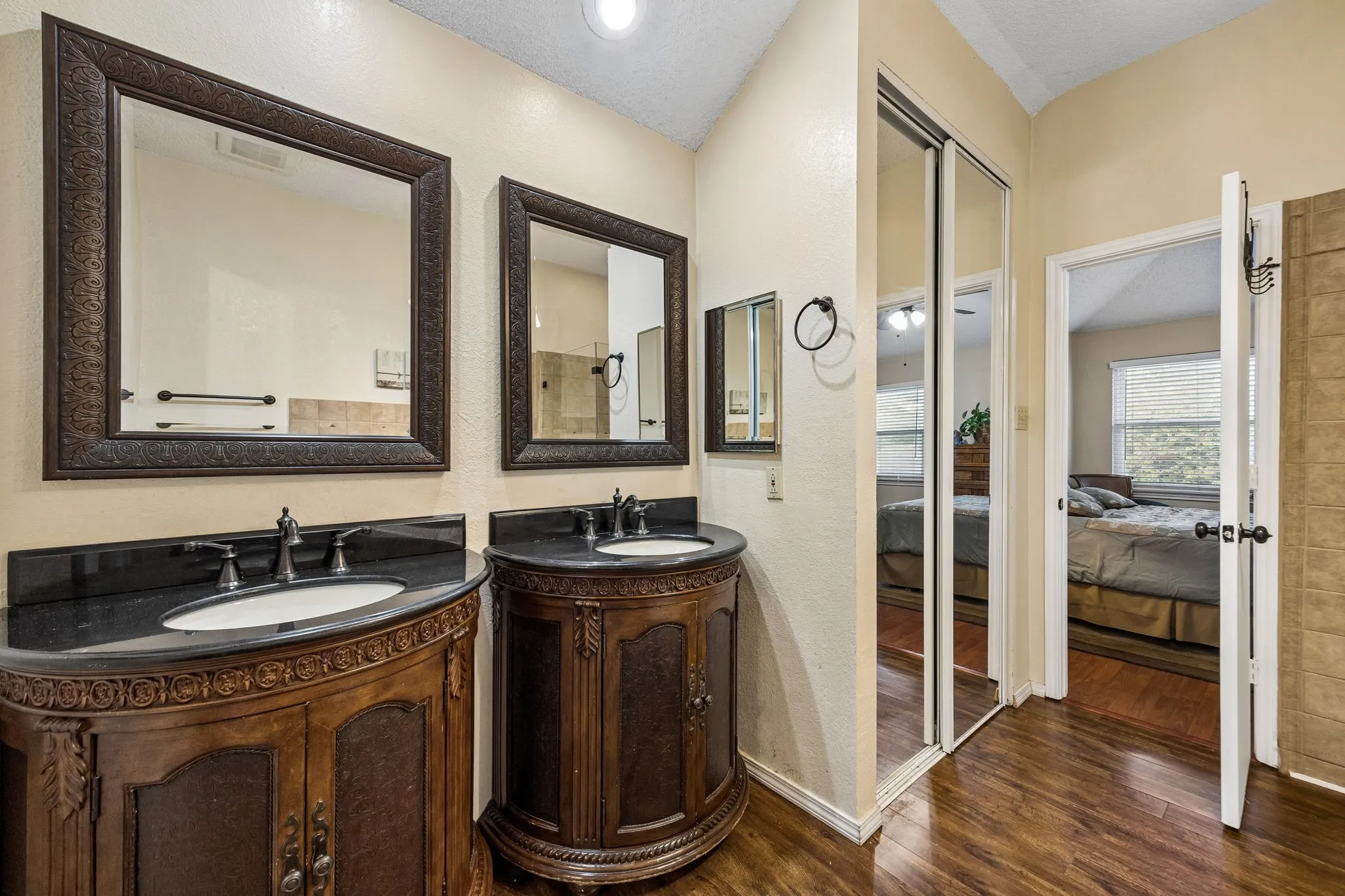 Dual wood-finish vanities with undermount sinks and dark countertops