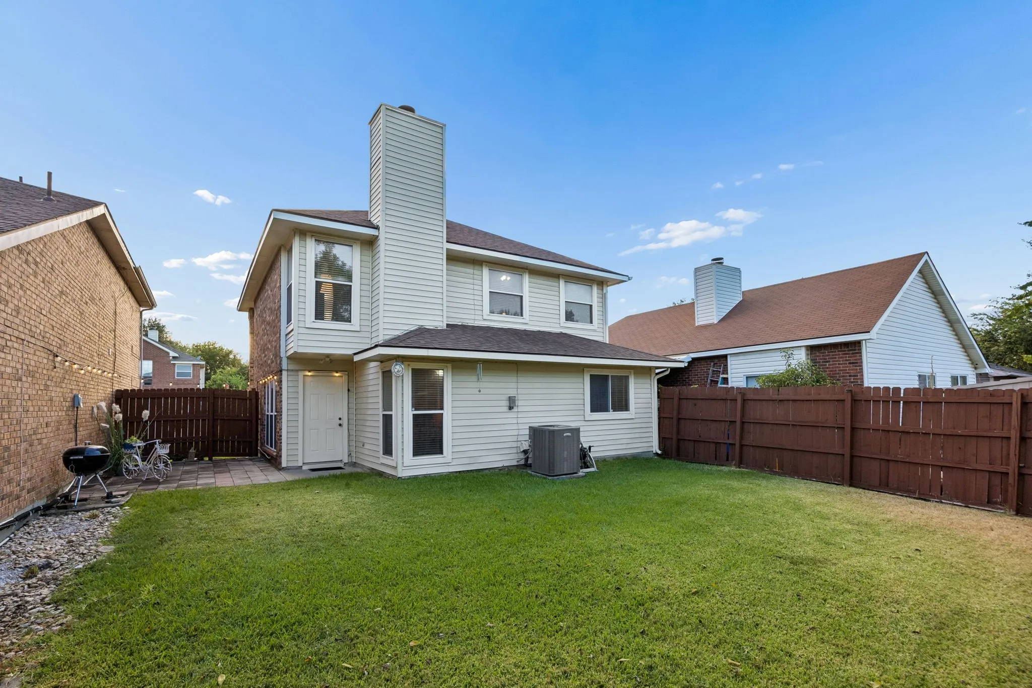 Expansive backyard featuring a manicured lawn, full privacy fencing, and a paved patio area