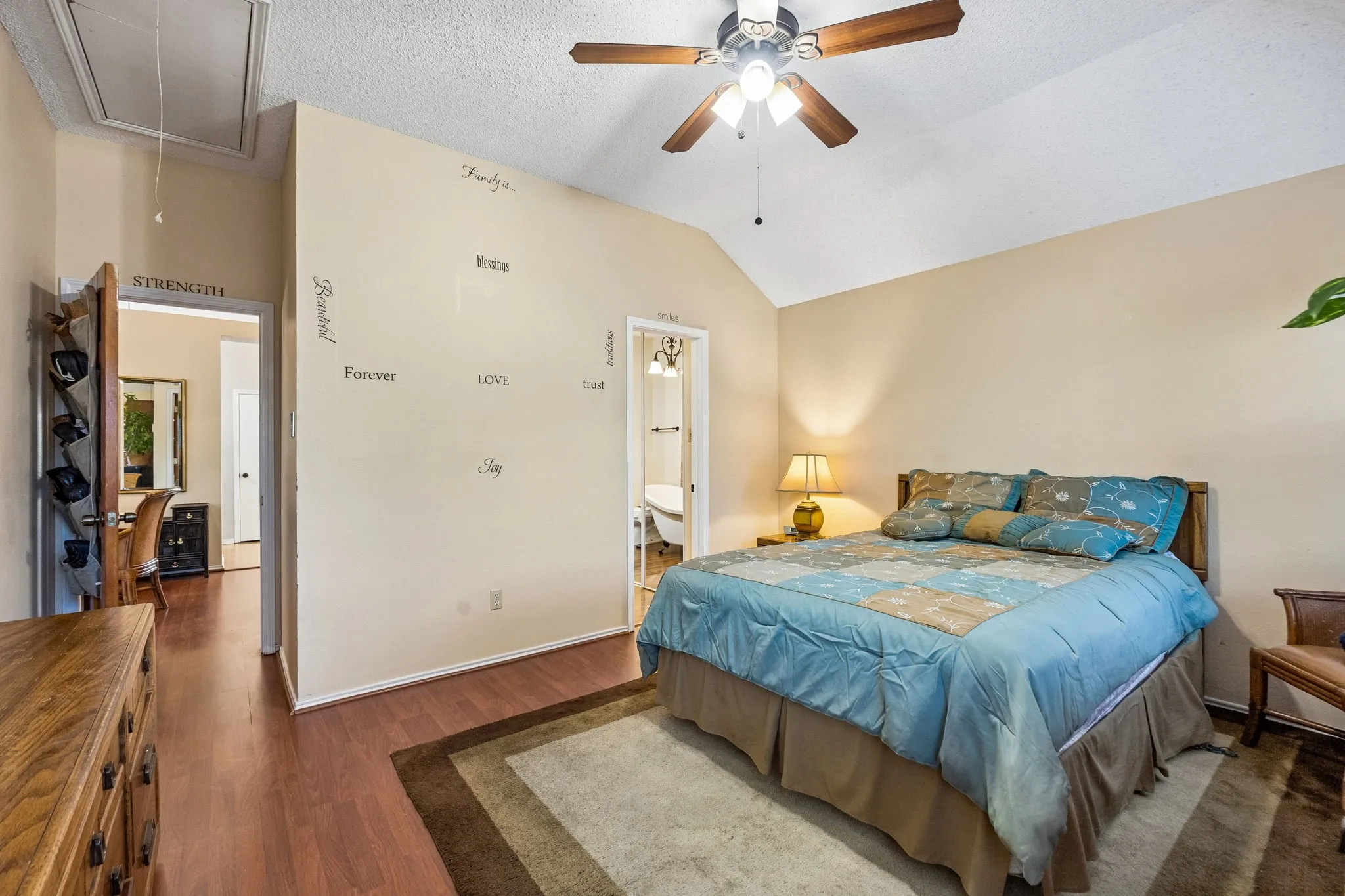 Vaulted ceiling with a ceiling fan, wood-finish flooring, and light-toned walls