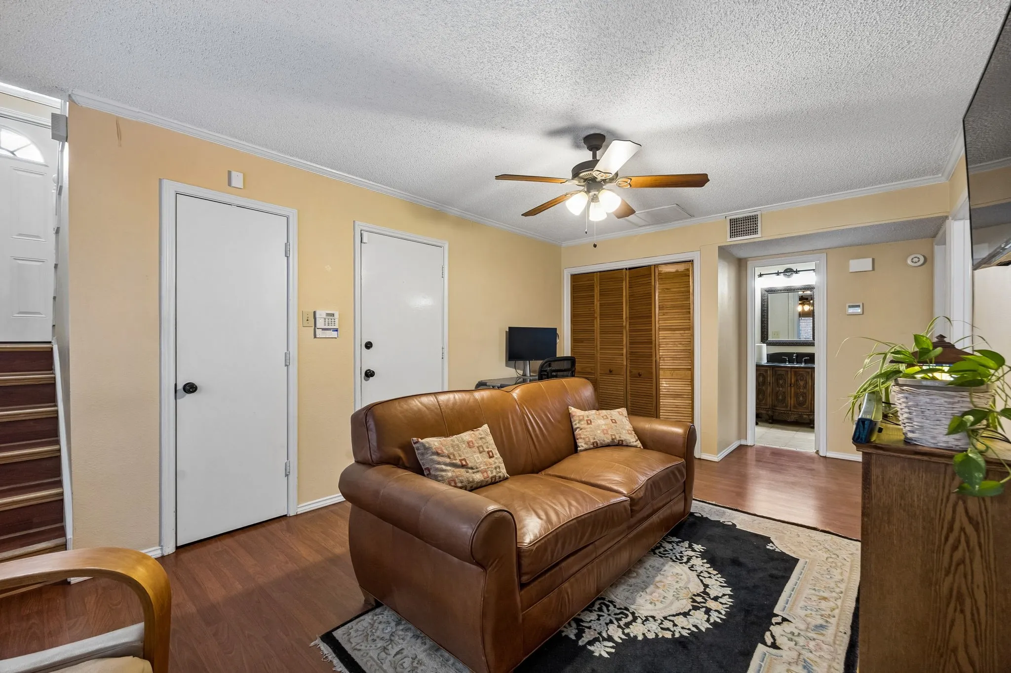 Wood-finish flooring throughout, ceiling fan with light fixture, and louvered bifold closet doors