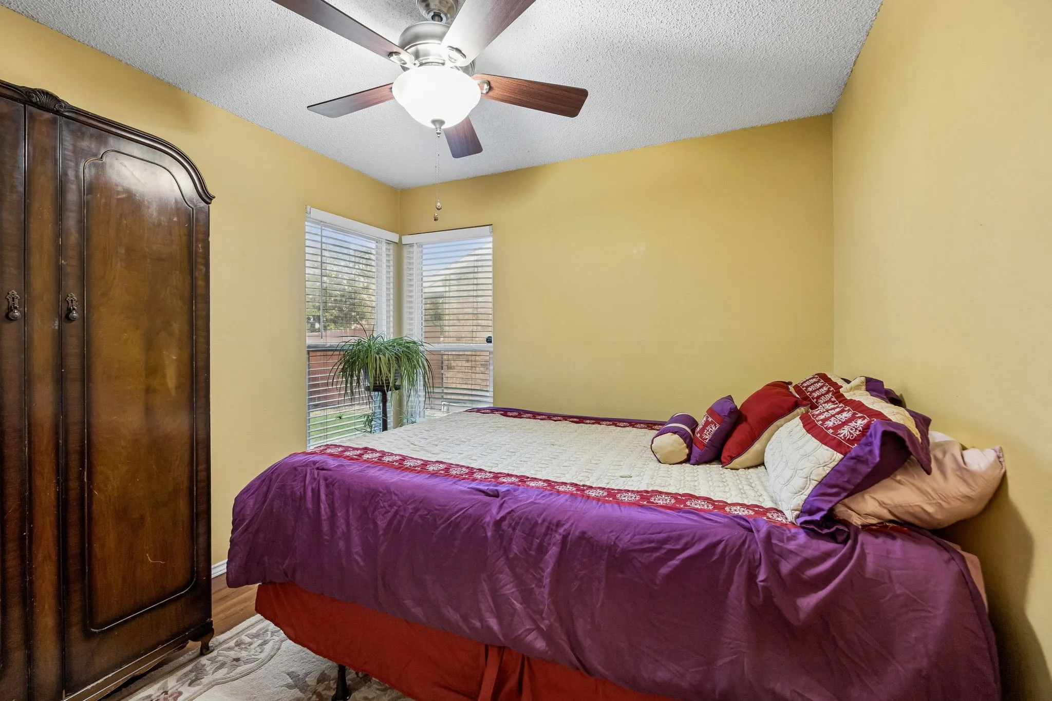 Corner windows with blinds, ceiling fan with integrated lighting, textured ceiling