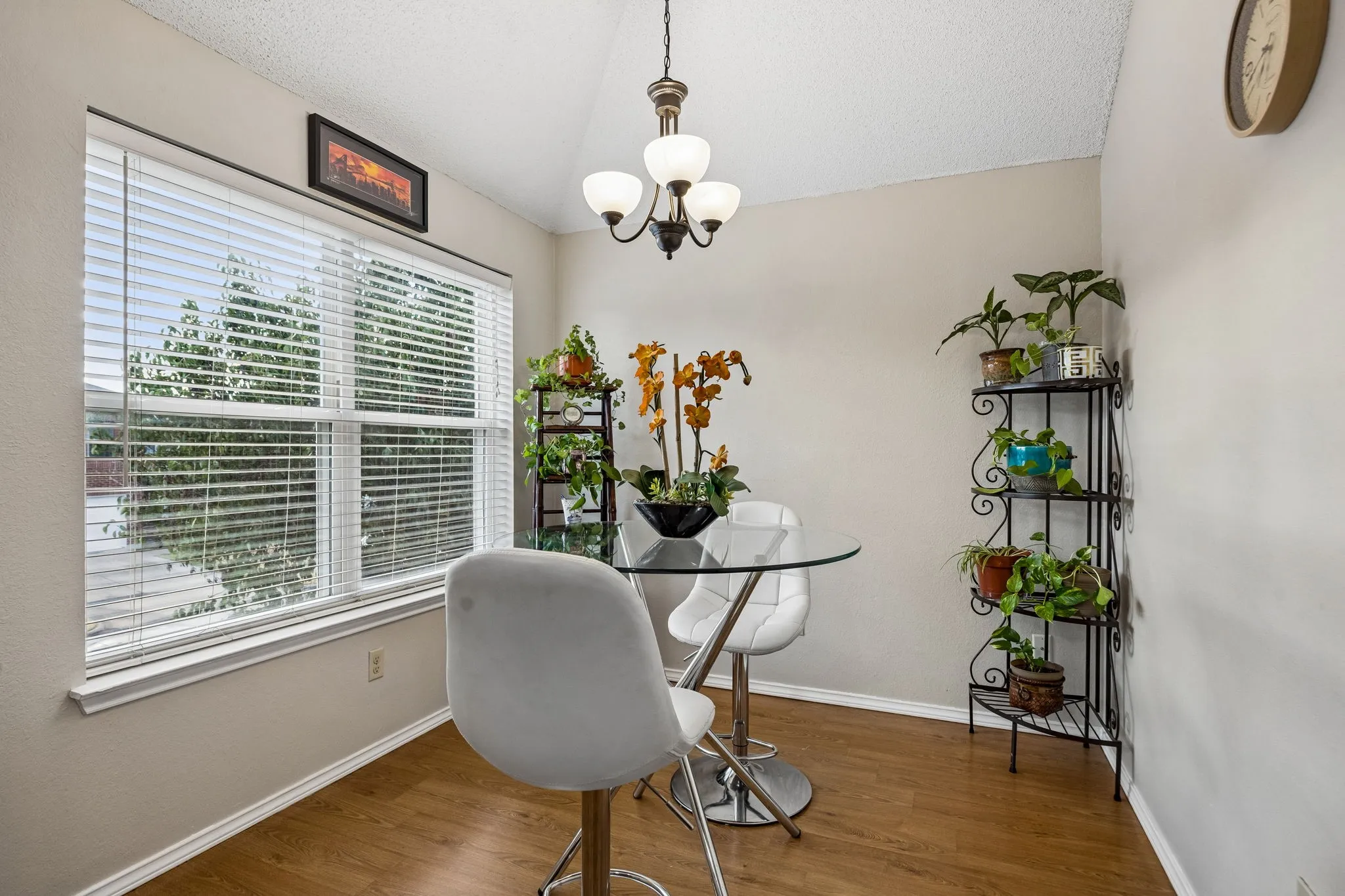 Wood-finish flooring with white trim and a large window featuring horizontal blinds