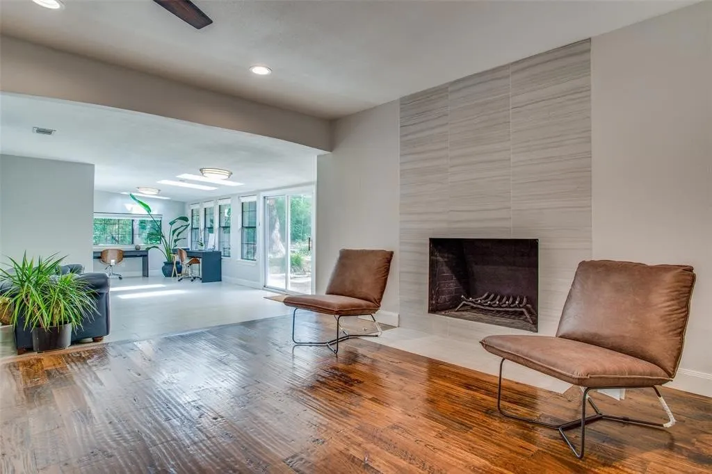 Hardwood flooring, recessed lighting, and a fireplace with a tiled surround