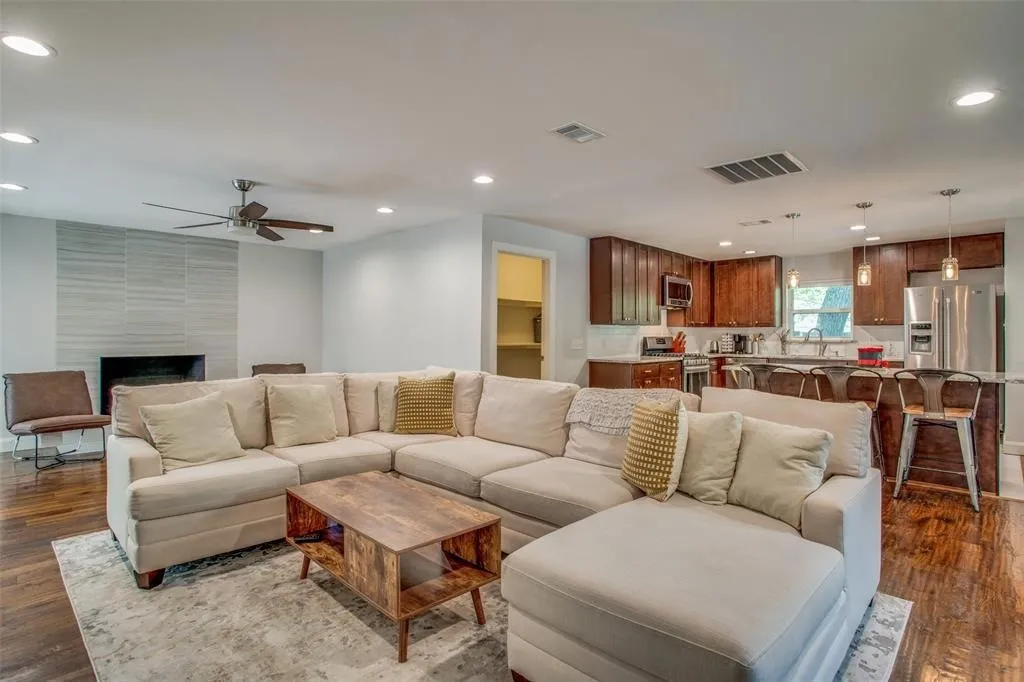 Open-concept living area featuring wood-finish flooring, a tiled fireplace surround, recessed lighting, and a ceiling fan