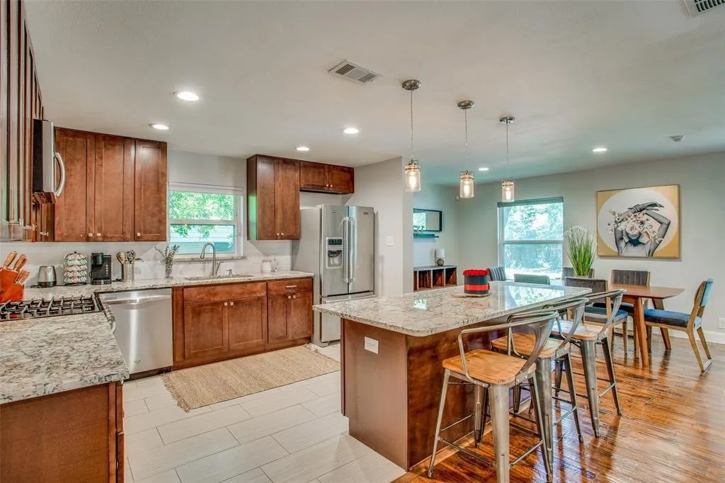Well-appointed kitchen featuring wood cabinetry, granite countertops, stainless steel appliances, and a large central island with pendant lighting