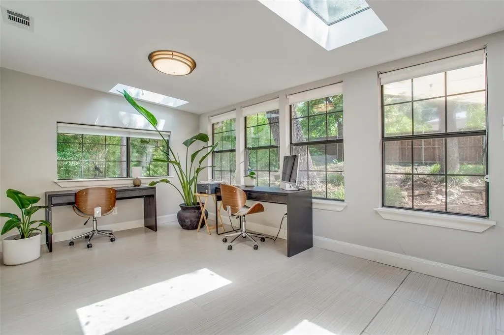 Room with two skylights, multiple windows, and light-toned wood-finish flooring