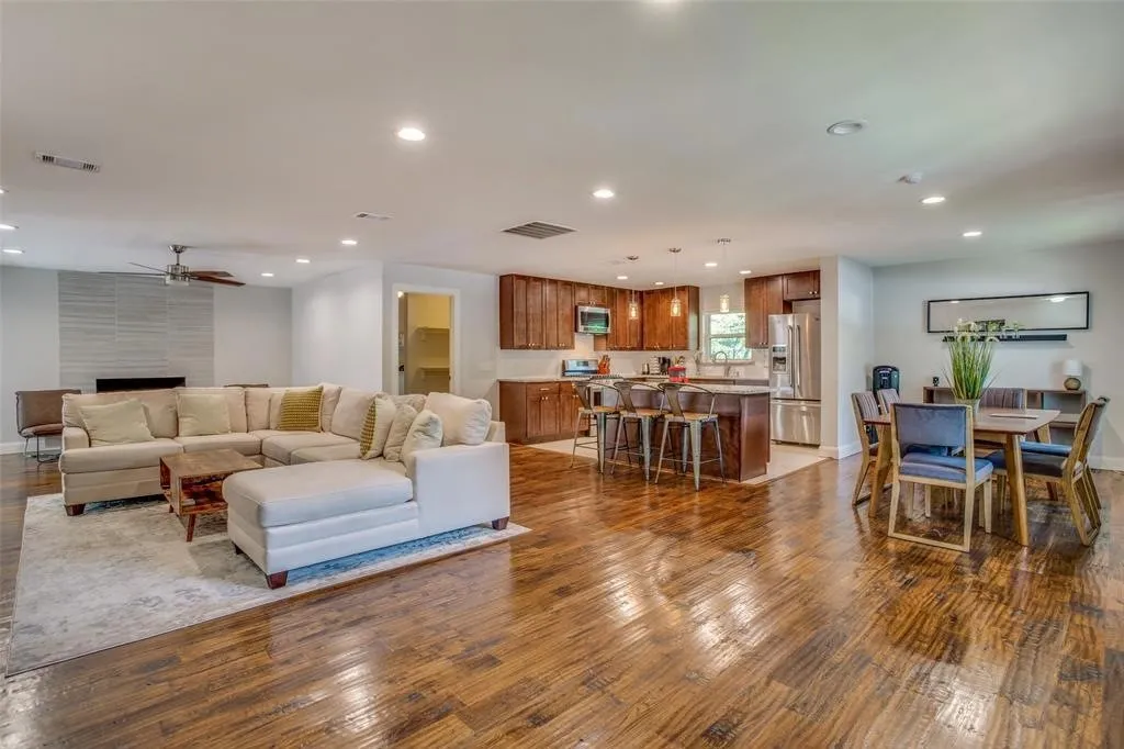 Open-concept living area featuring wood-finish flooring, a contemporary fireplace with tile surround, recessed lighting, and a ceiling fan