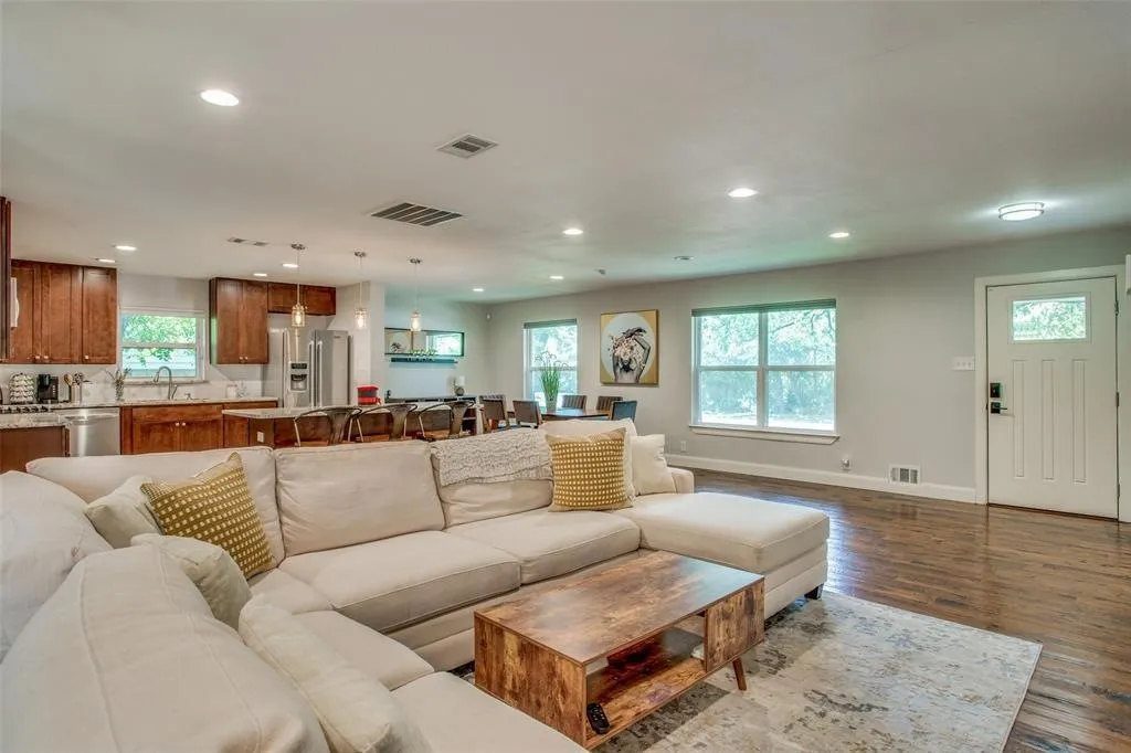Open-concept living area with wood-finish flooring, recessed lighting, and multiple windows