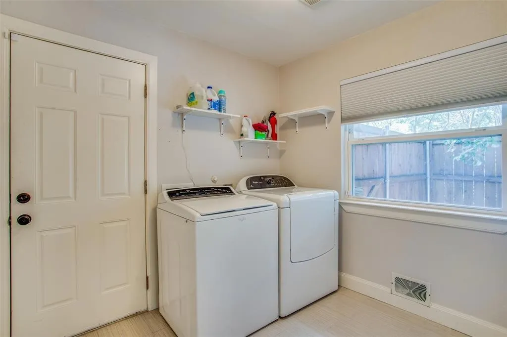 Laundry area with wood-finish flooring, a paneled door, and a single window with a privacy blind