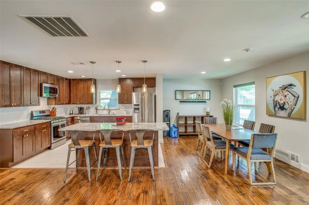 Open-concept layout featuring wood-finish flooring, recessed lighting, and a kitchen island with pendant fixtures