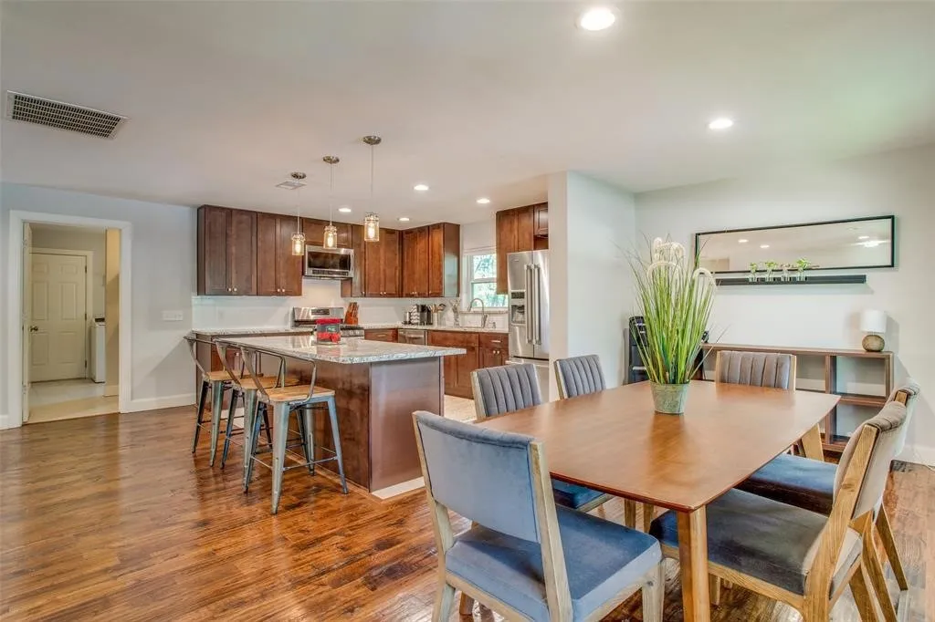 Wood-finish flooring throughout, kitchen island with seating, stainless steel appliances, recessed lighting, and pendant lights