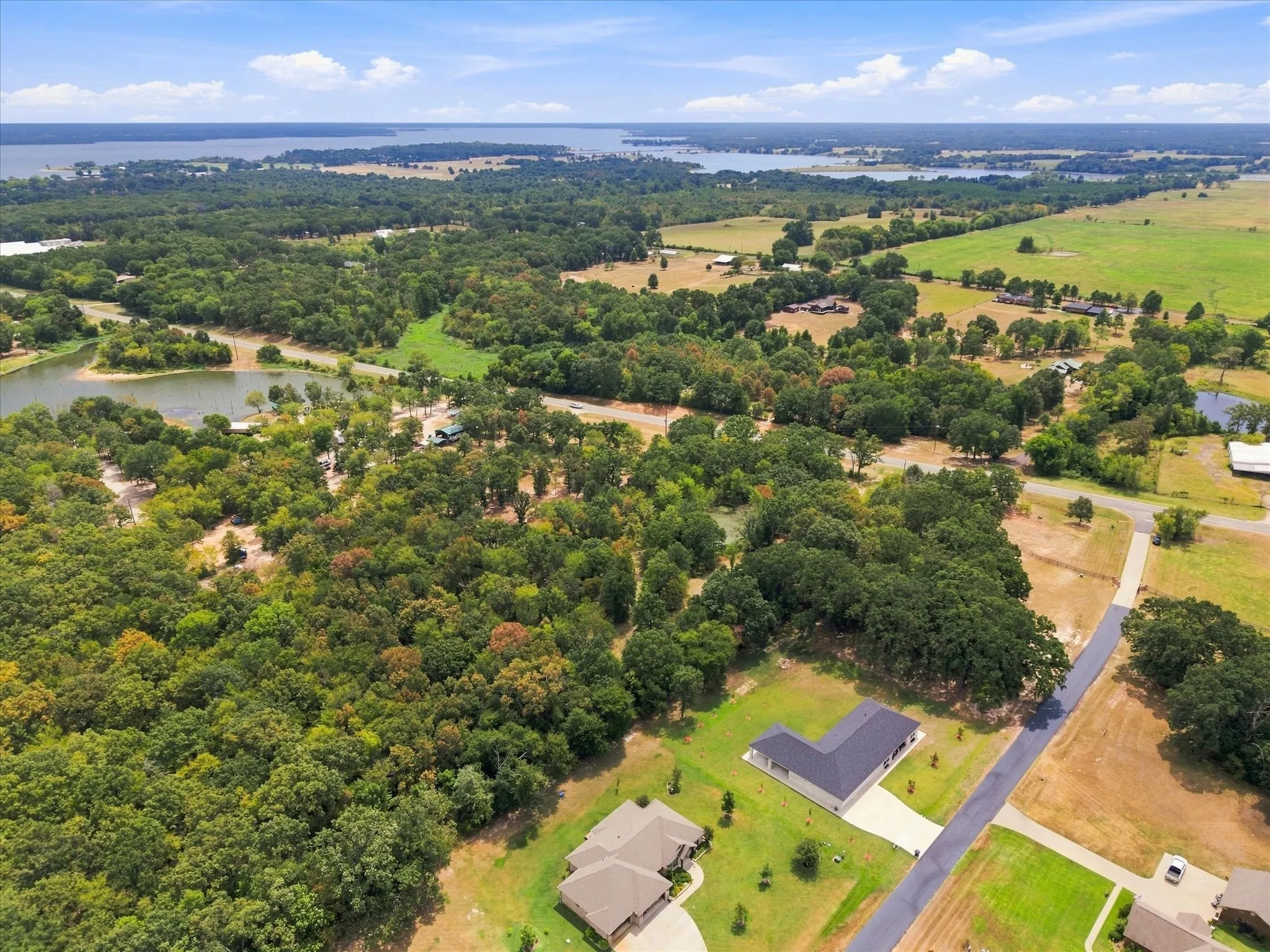 Expansive landscape featuring dense tree coverage, open fields, and two bodies of water