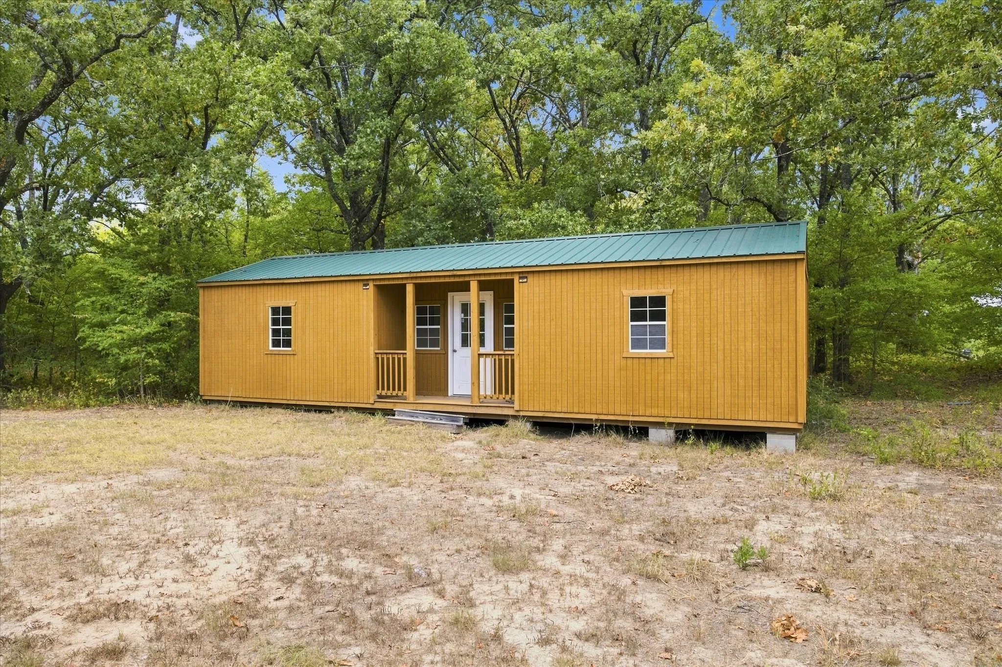 Compact structure with a covered front porch and a green metal roof