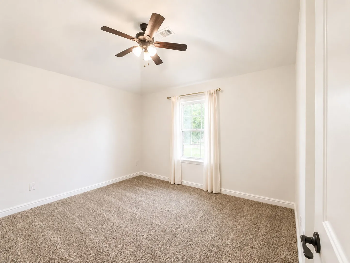 Carpeted flooring, white walls, ceiling fan with integrated lighting, window with trim, and a paneled door with dark hardware