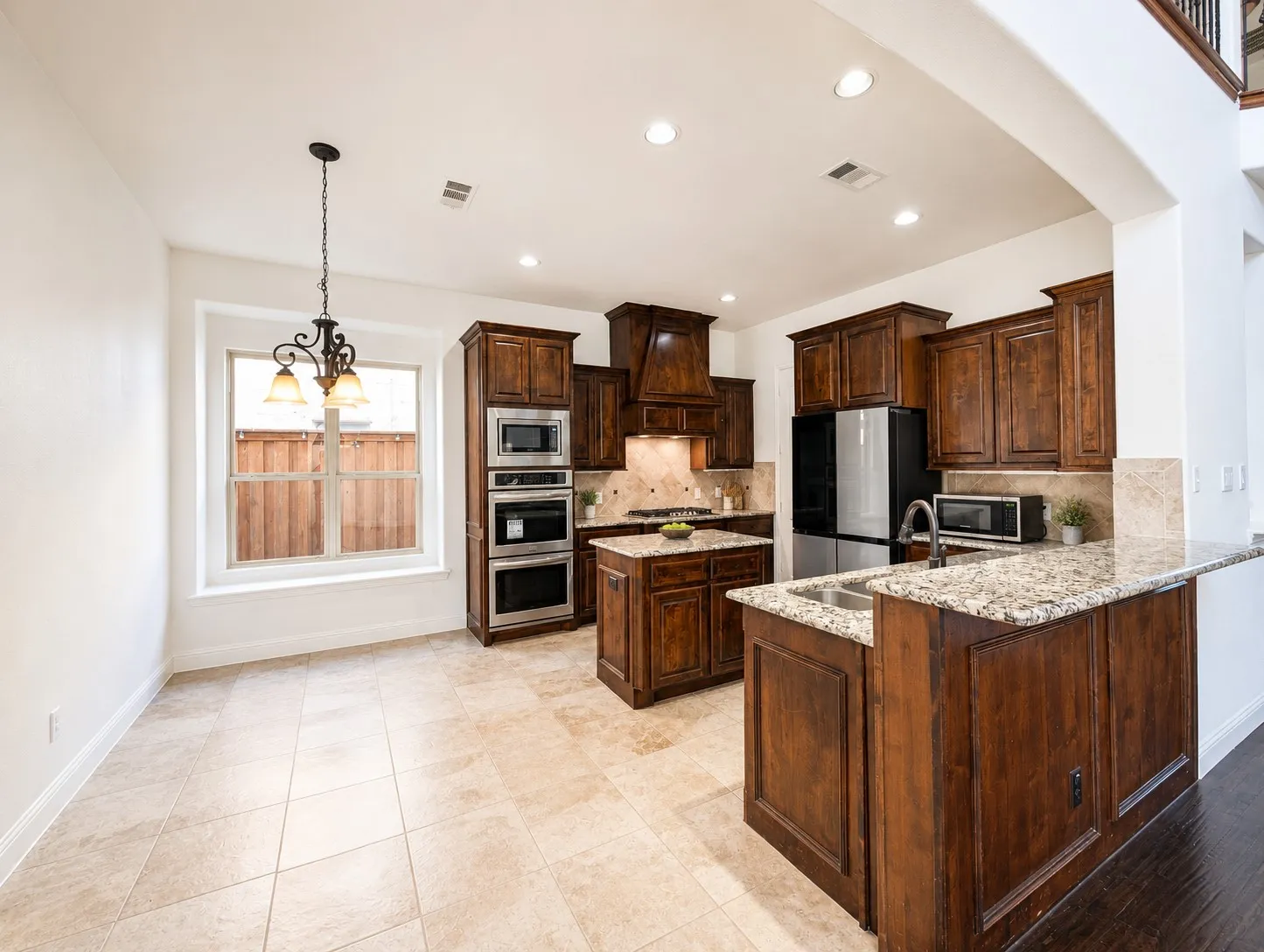 Kitchen featuring wood-finish cabinetry, stainless steel appliances, granite countertops, and tile flooring