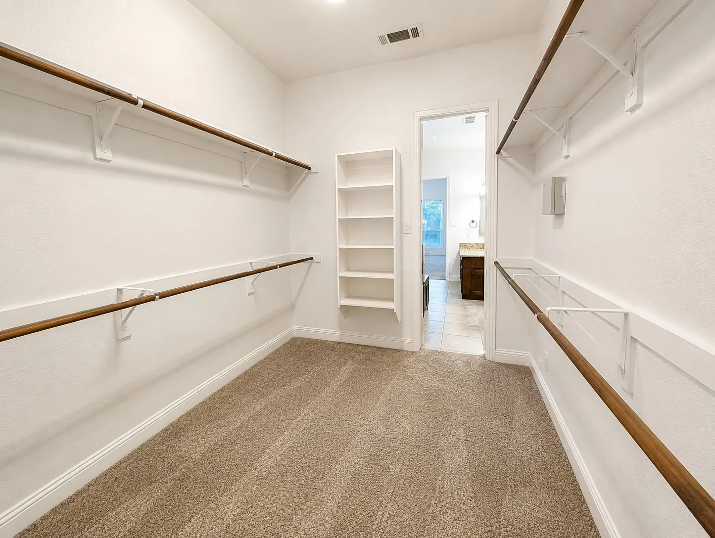 Walk-in closet featuring carpet flooring, built-in shelving, and multiple hanging rods