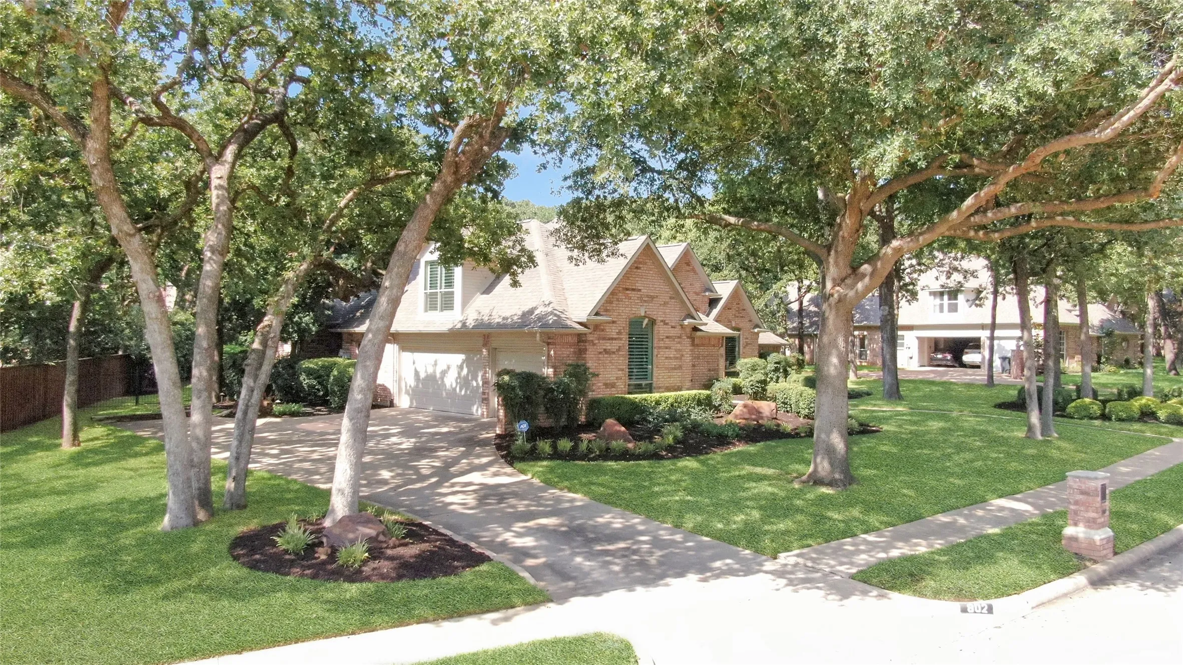 View of 3-car garage and lush landscaping