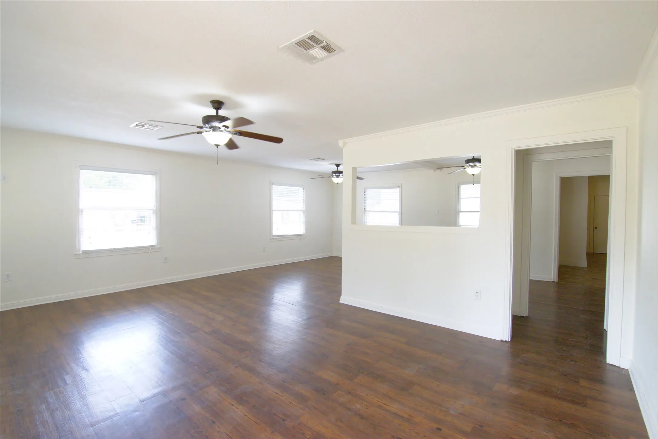 lots of living space with Viynl plank flooring flooring, white walls, multiple windows, and ceiling fans with integrated lighting