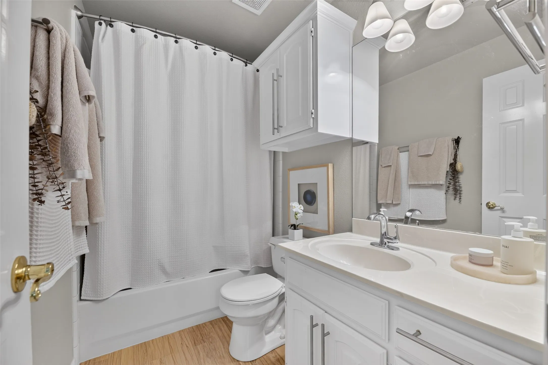 White vanity with integrated sink, chrome faucet, and expansive mirror