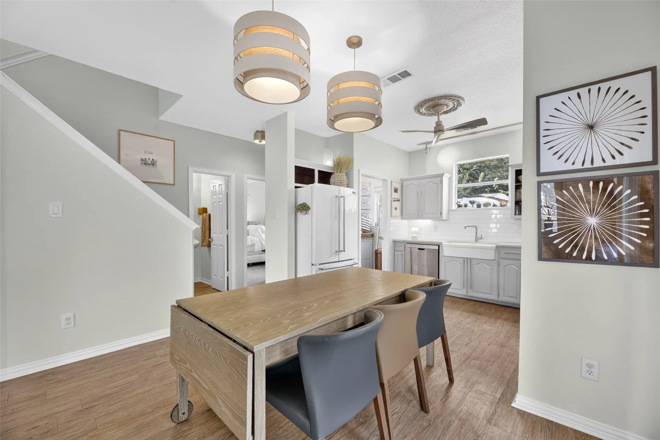 Wood-finish flooring, recessed lighting, two drum pendant lights, white subway tile backsplash, and a farmhouse sink