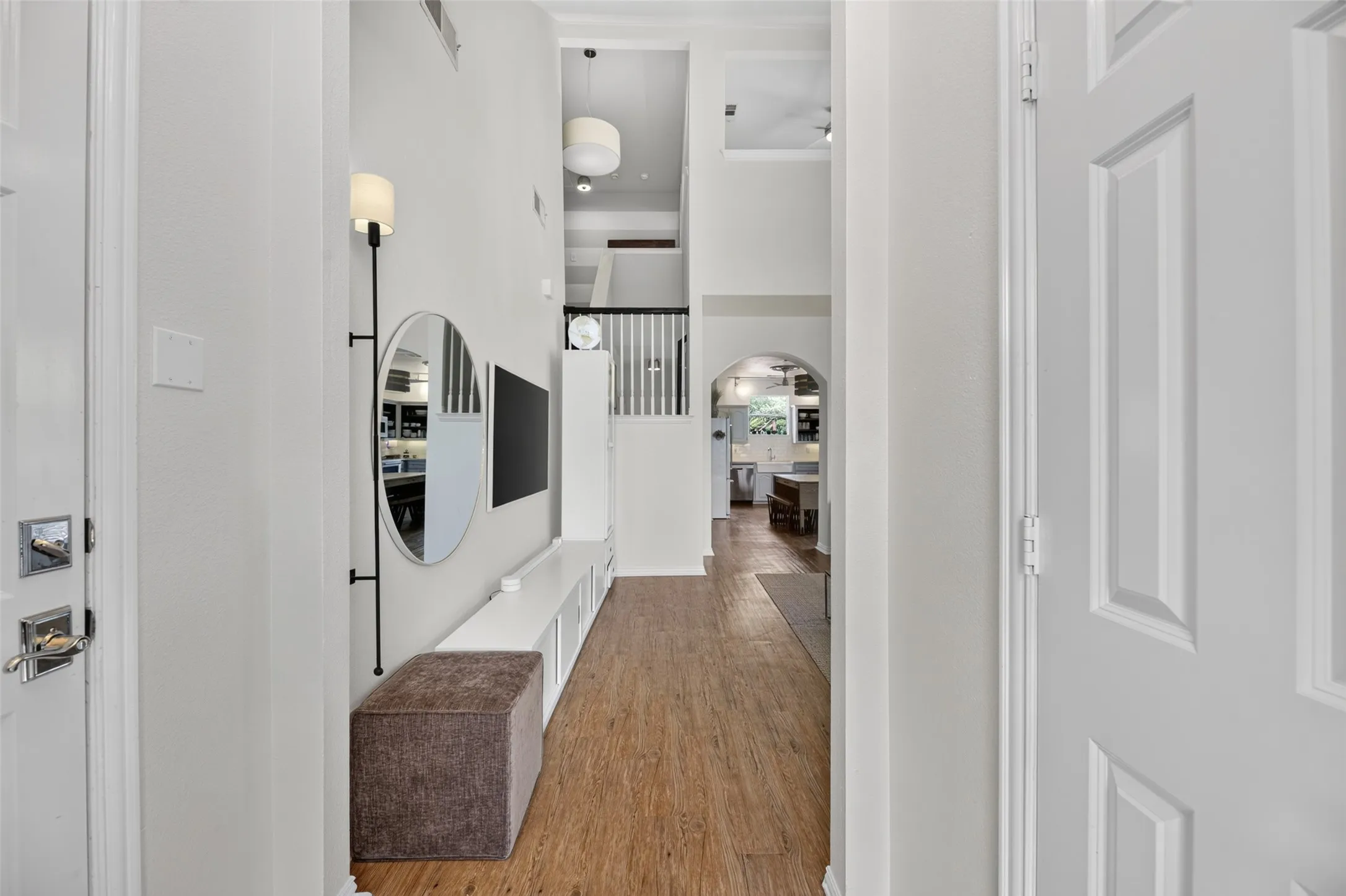 Elongated entryway featuring wood-finish flooring, high ceilings, and a built-in media console