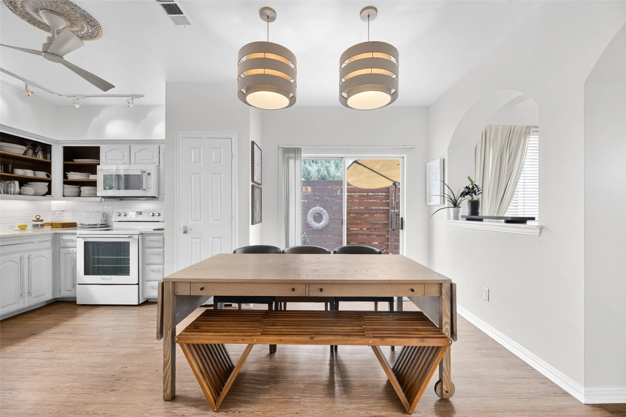 Wood-finish flooring, white cabinetry, stainless steel appliances, recessed lighting, and a ceiling fan