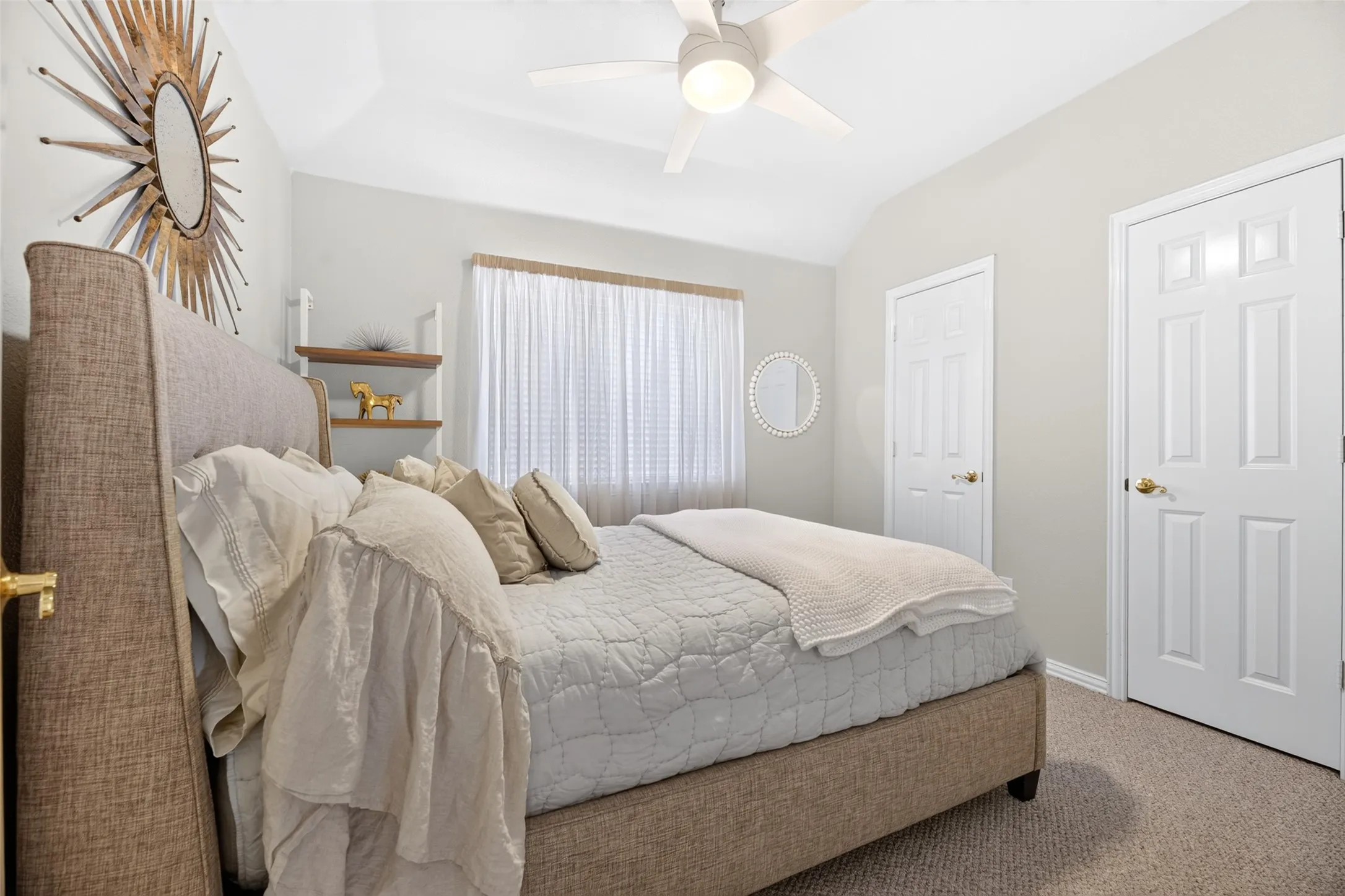 Vaulted ceiling, ceiling fan with integrated lighting, window with sheer treatments, white paneled doors, and neutral carpet flooring