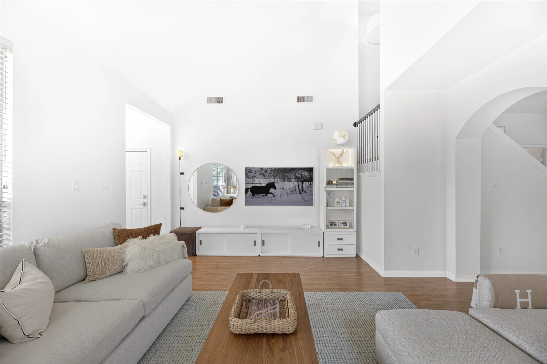 Vaulted ceiling, wood-finish flooring, built-in media console, built-in shelving unit, arched doorway
