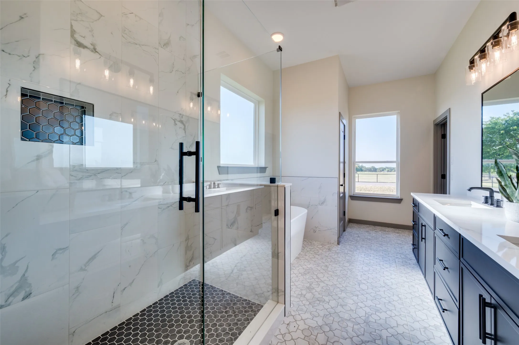 Glass-enclosed shower with honeycomb tile flooring and an integrated niche