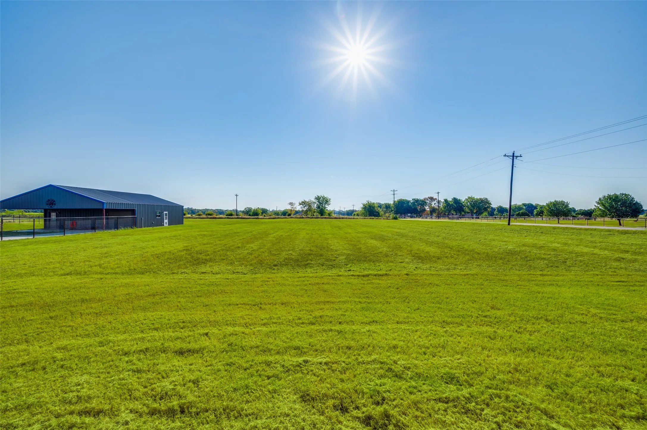 Expansive green space featuring a metal-sided building with a dark roof and white trim