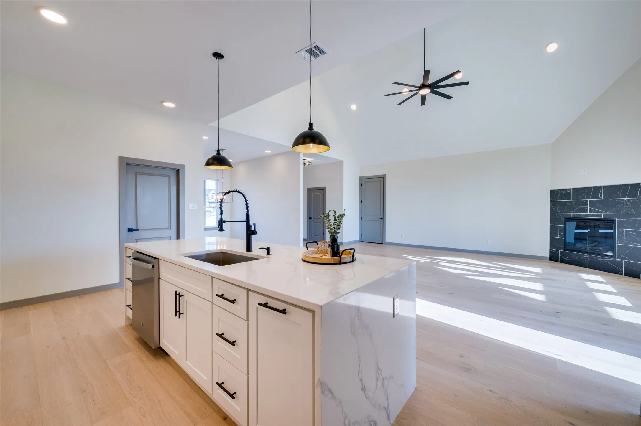 Kitchen island with white cabinetry, stainless steel dishwasher, and quartz countertop