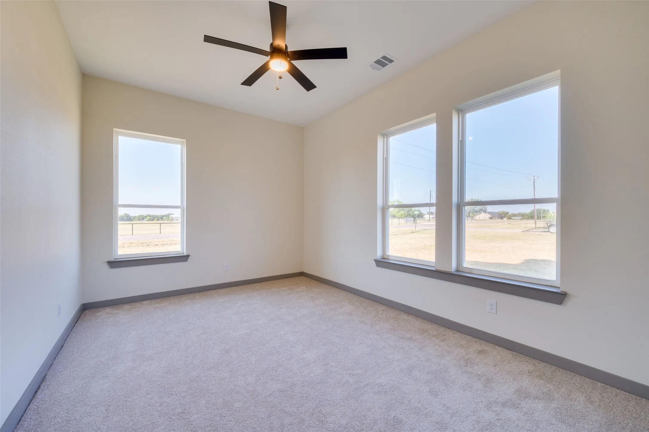 Carpeted room featuring multiple windows, a ceiling fan, and sloped ceiling