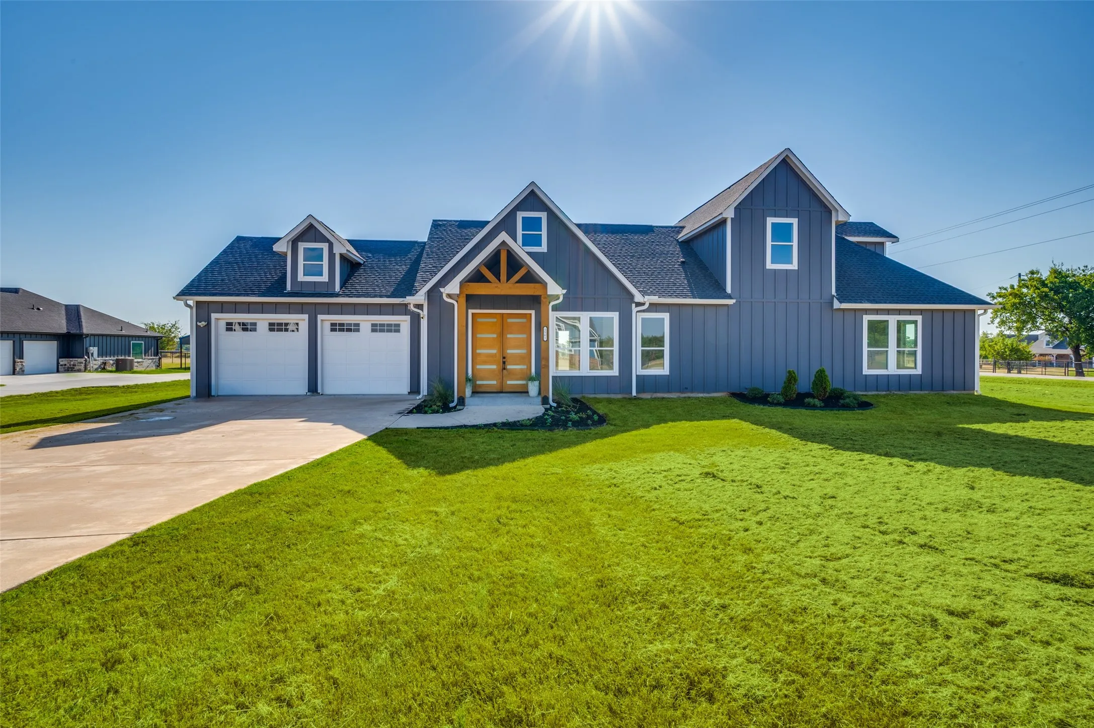 Board and batten siding with white trim, a dark shingle roof, and a two-car garage