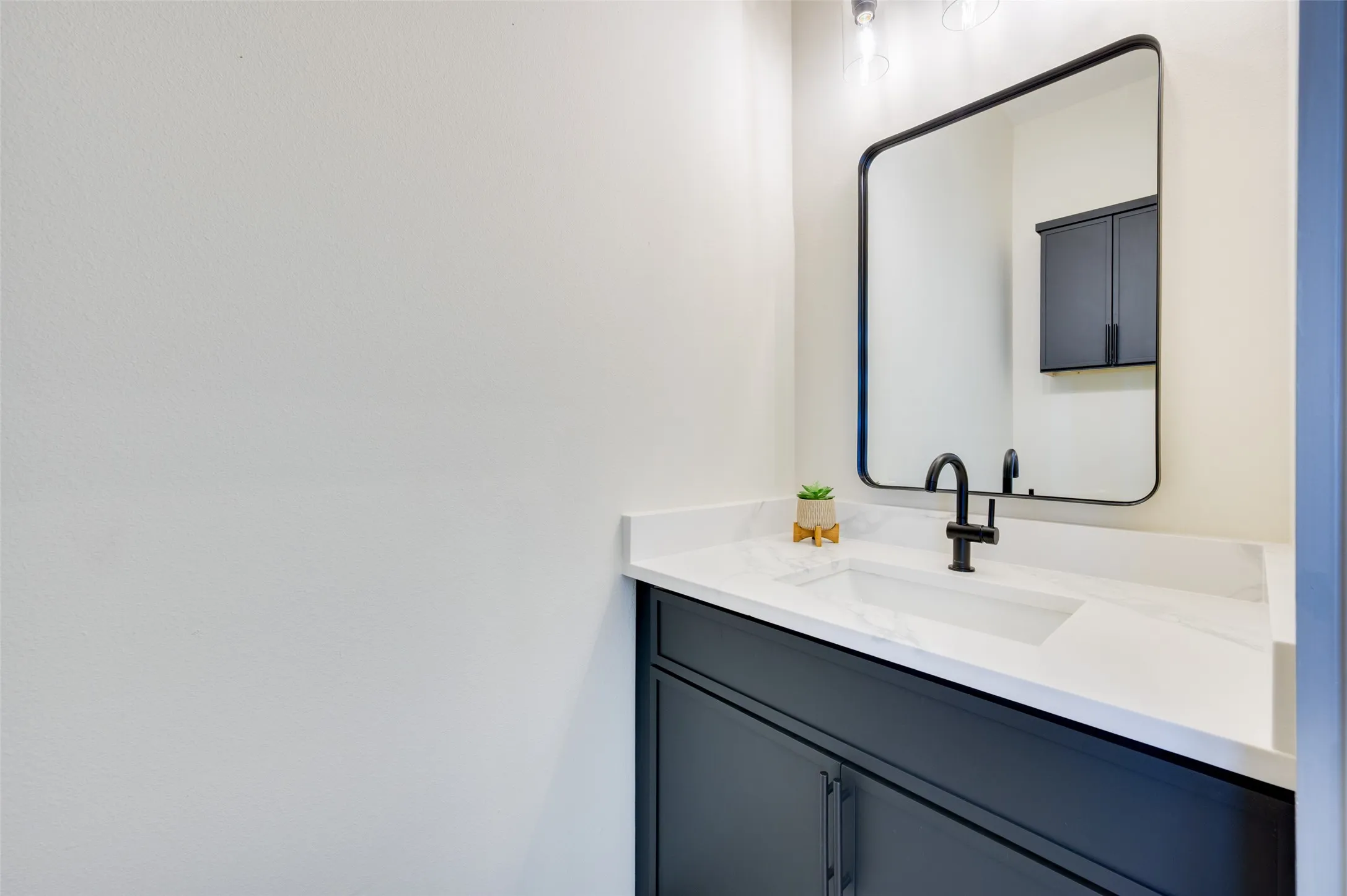 Vanity with dark cabinetry, integrated sink, and white countertop