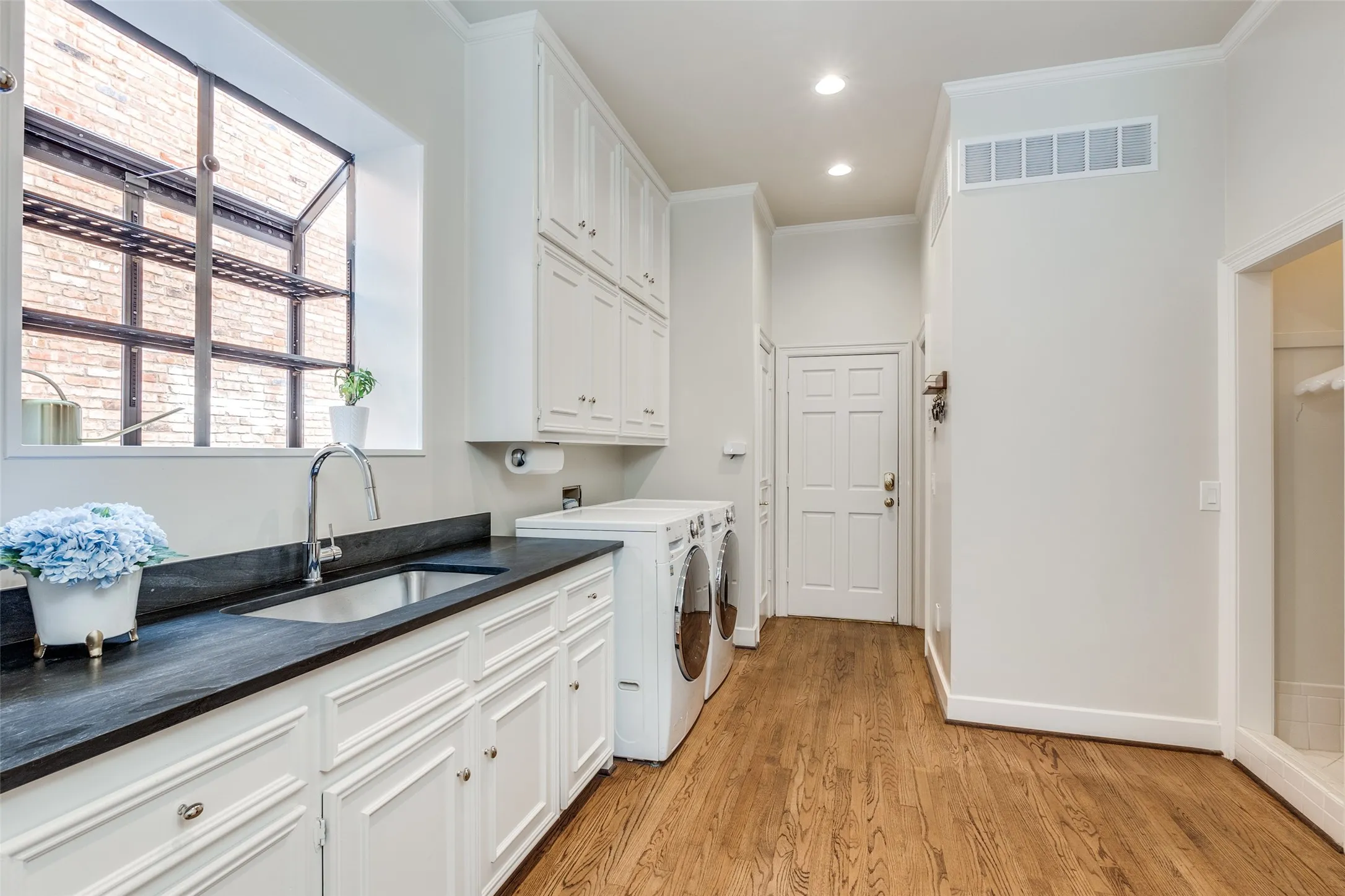 Spacious laundry room between garage entry and kitchen offer full size W/D, sink storage, drip dry area, half bath, and elevator to the second level
