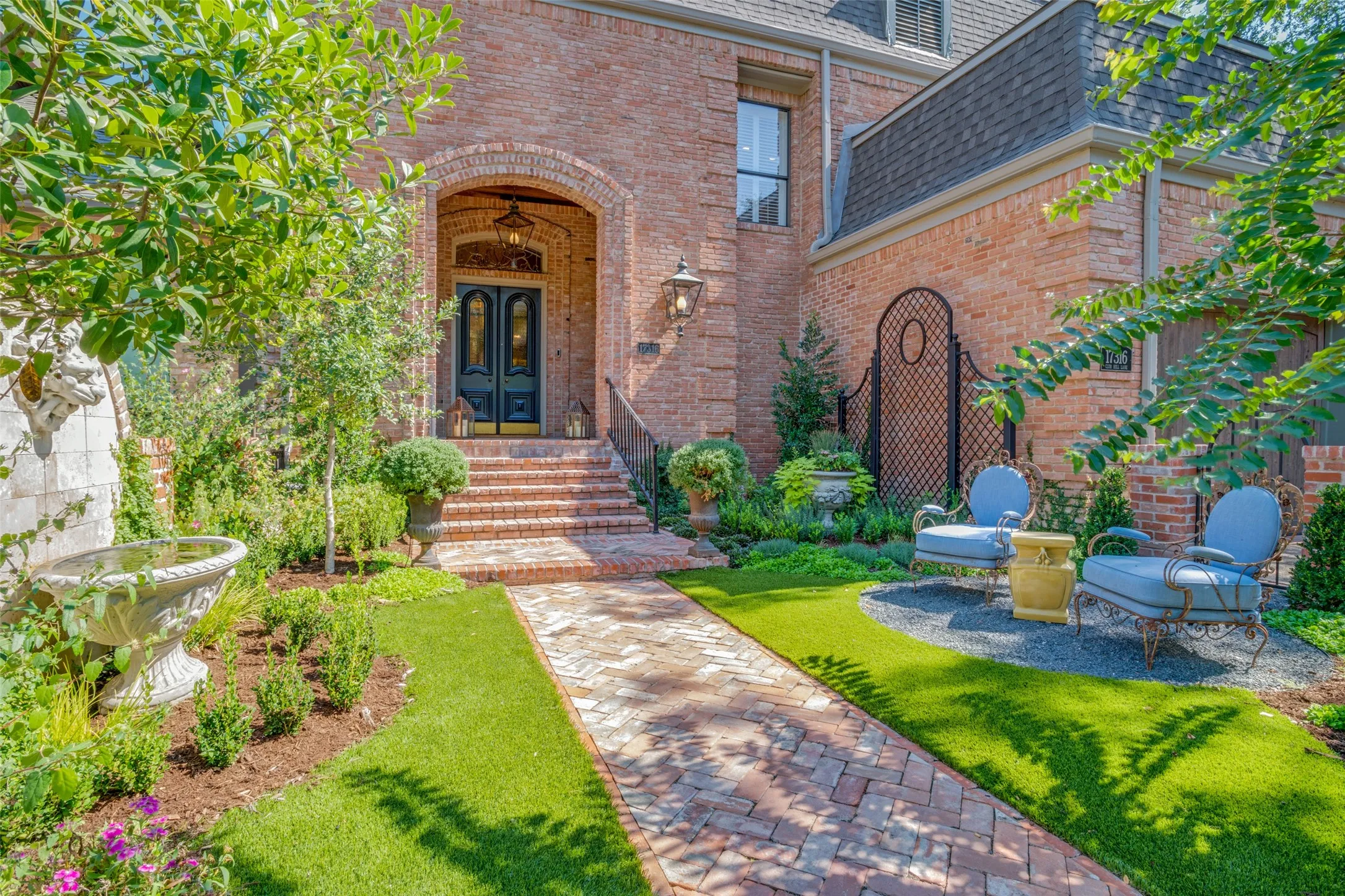Welcoming entry garden with turf, lush landscape, sitting area and fountain