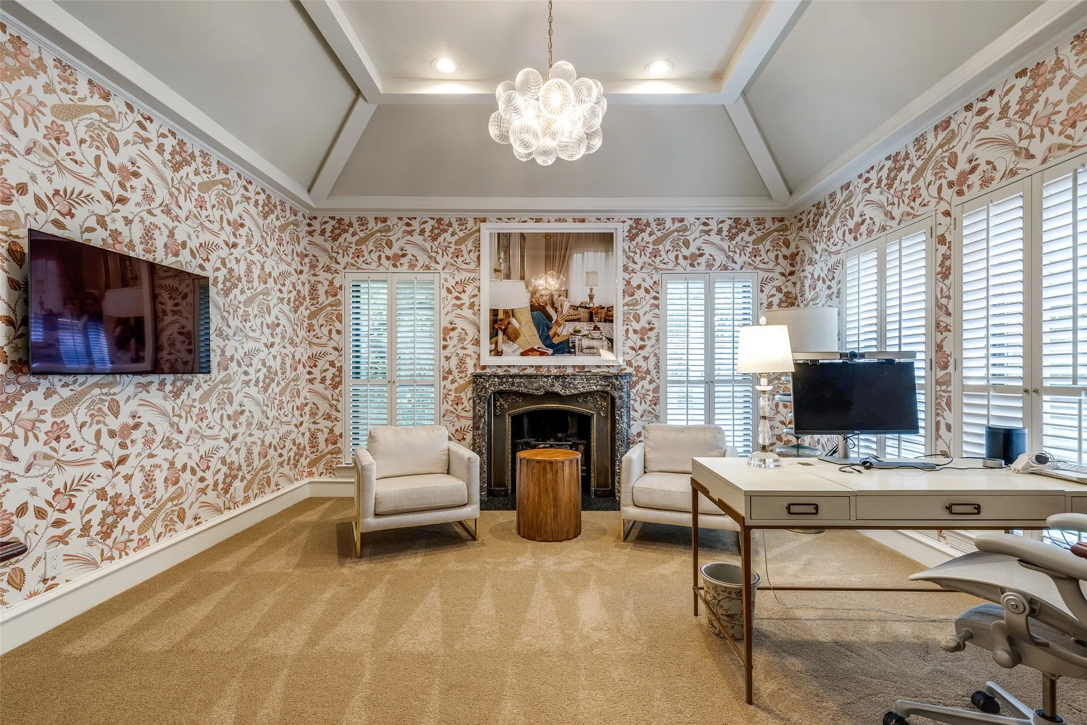 This flexible primary suite room offers thoughtful lighting, designer wallpaper, and a warm fireplace. This could be used as an additional sitting room, exercise room or office.