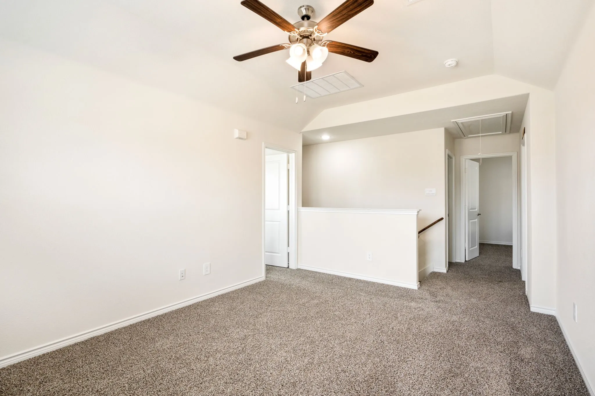 Carpeted room featuring a ceiling fan with light kit, vaulted ceiling, and painted white walls