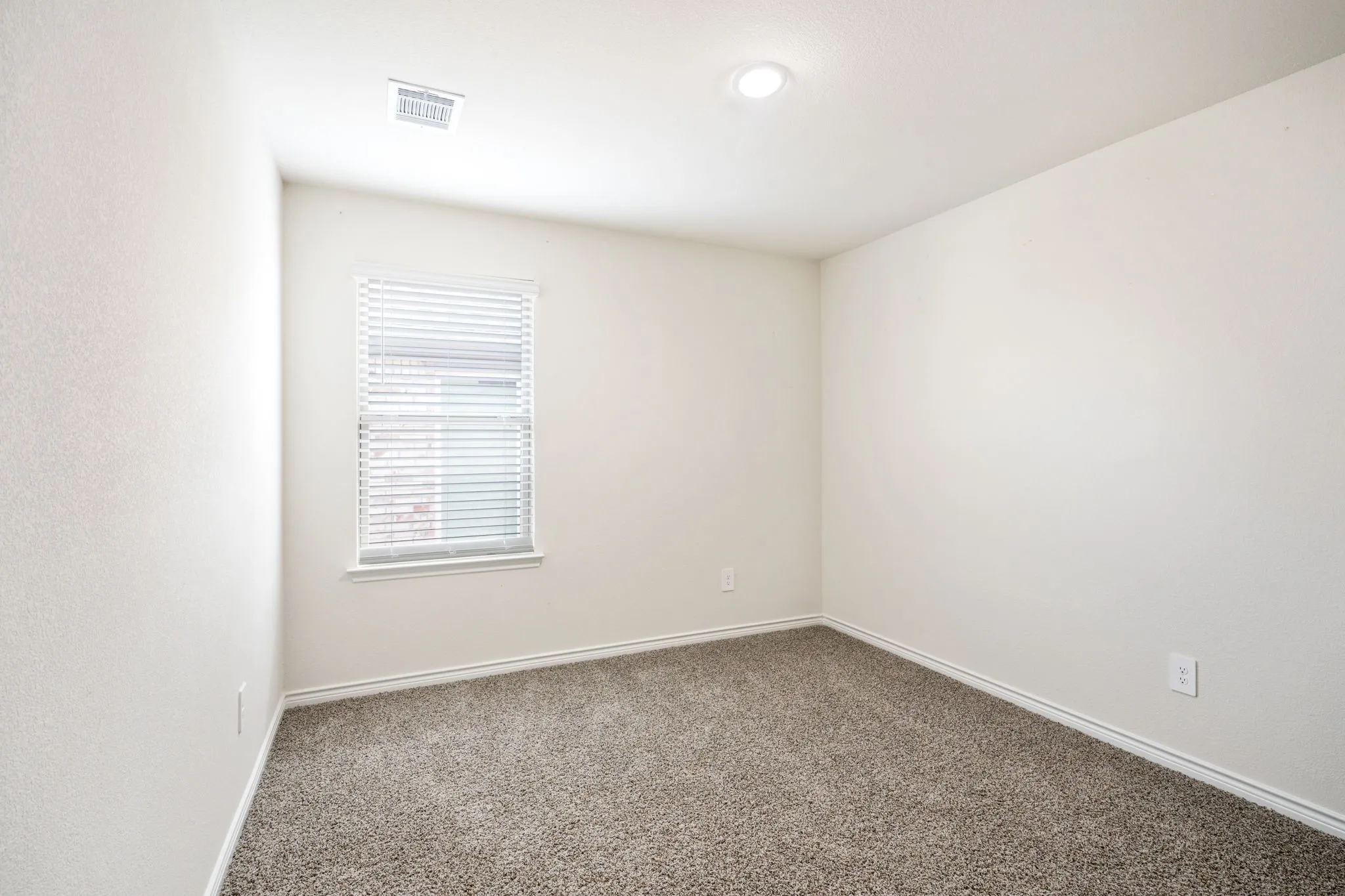 Neutral wall color, recessed ceiling lighting, window with blinds, and textured carpeting
