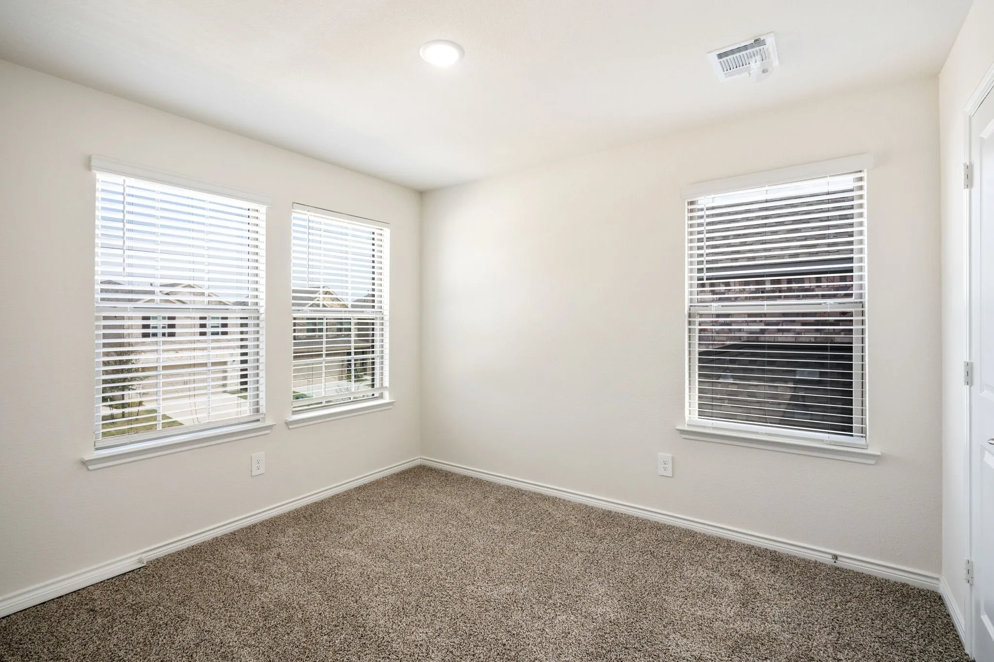 Plush carpet flooring with white trim, recessed lighting, and three windows with blinds