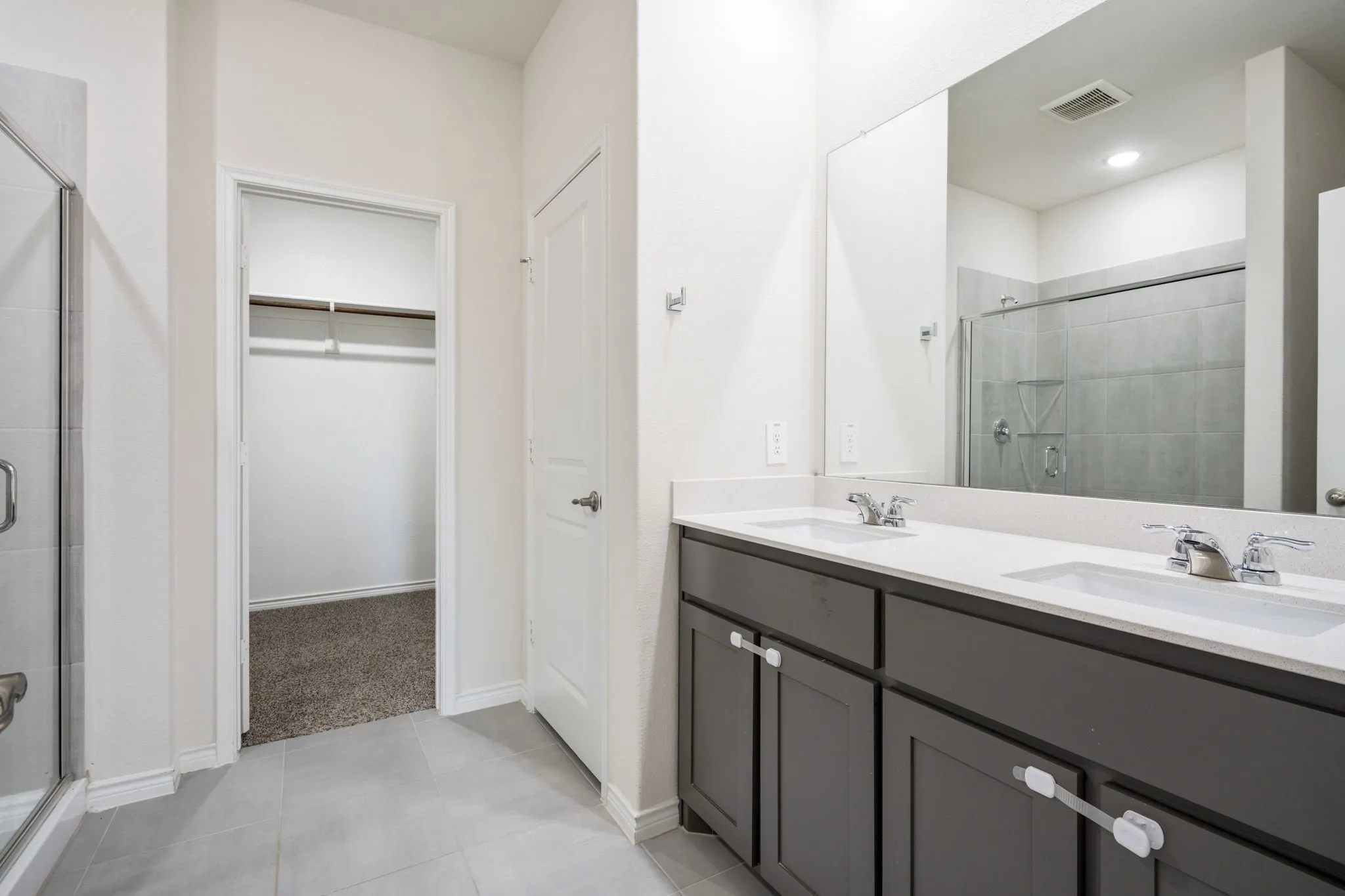 Dual vanity with integrated sinks, chrome fixtures, and grey cabinetry