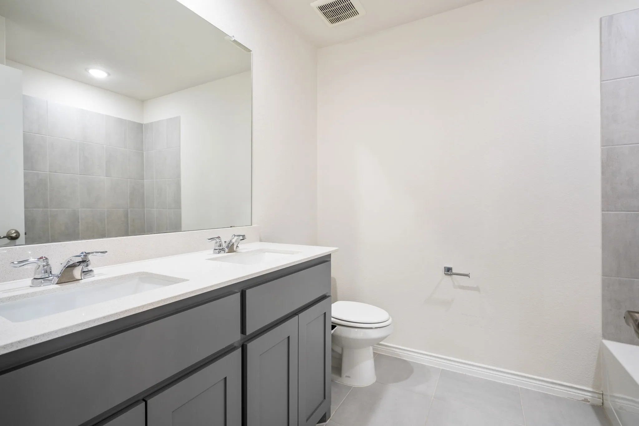 Double vanity with white countertop, chrome fixtures, and a large mirror