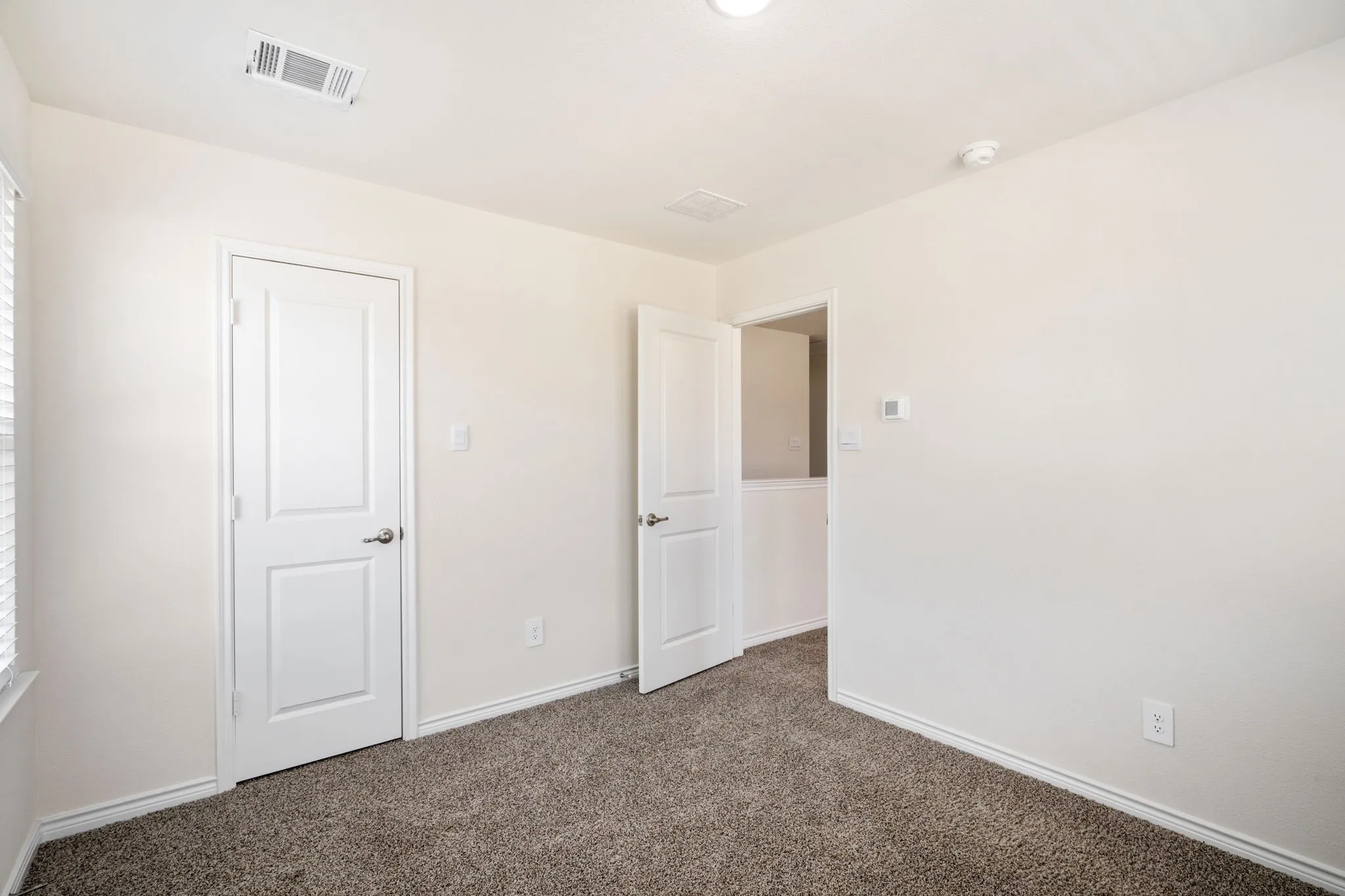Neutral wall paint, textured carpet flooring, white paneled doors, and a ceiling light fixture