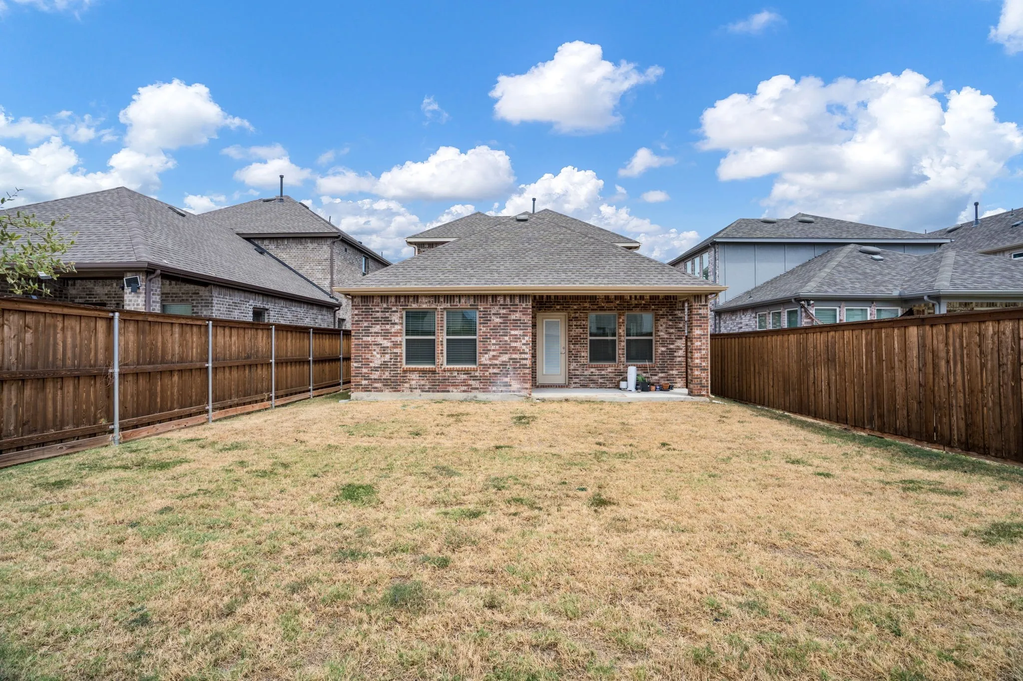 Brick exterior with a covered patio and a privacy fence