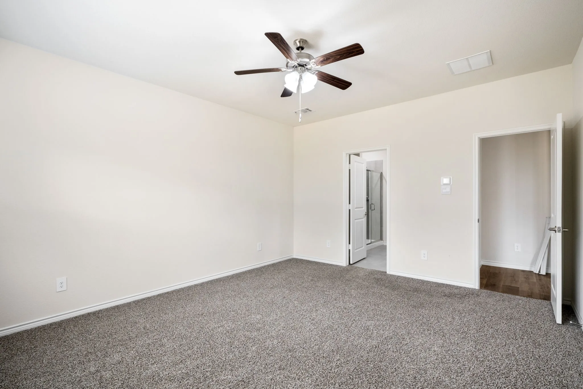 Spacious room with plush gray carpeting, neutral wall finishes, and a ceiling fan with integrated lighting